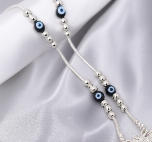 Silver evil eye anklet on white satin cloth